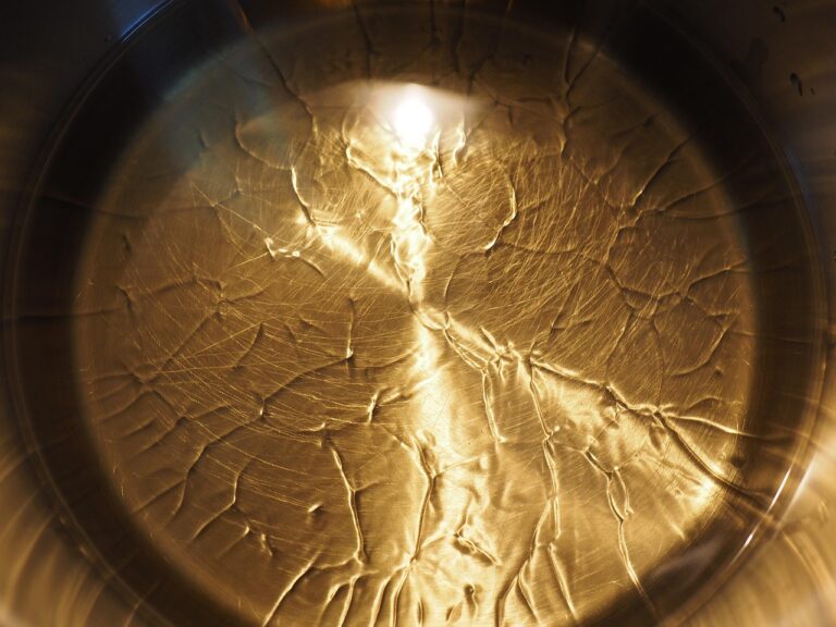 Immagine di un soffritto in padella, con olio e verdure, mentre si aggiunge un cucchiaio d'acqua.