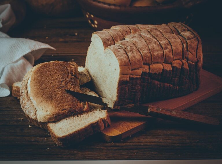Pane fresco su un tagliere di legno, circondato da ingredienti naturali per preservarne la freschezza.
