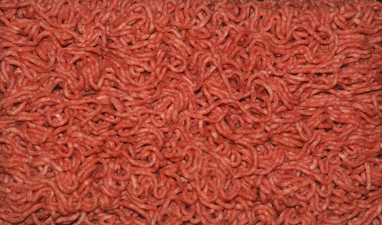 Carne macinata fresca con colore rosso vivo, contrastata da carne grigia come segnale di deterioramento.