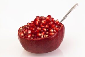 Melograno tagliato a metà, con un cucchiaio pronto per battere e sgranare i chicchi.