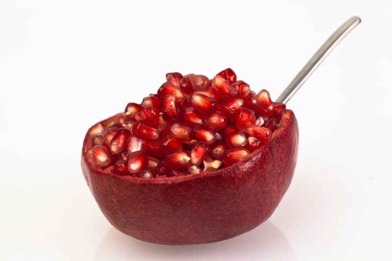 Melograno tagliato a metà, con un cucchiaio pronto per battere e sgranare i chicchi.