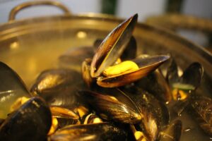 Cozze pulite con una paglietta d'acciaio, pronte per la cottura in un piatto.
