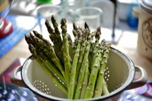 Asparagi cotti a vapore con punte fuori dall'acqua in una pentola.