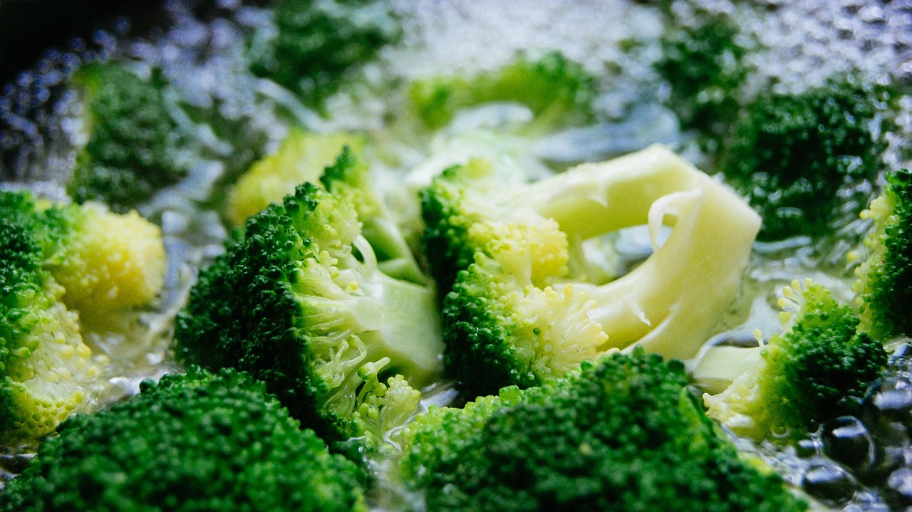 Immagine di broccoli in cottura con una fetta di pane imbevuta di aceto sul coperchio della pentola.